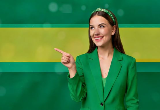 Kobieta w zielonej marynarce, wskazująca placem swojej prawej dłoni na jej prawą stronę.
